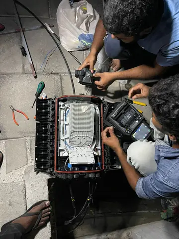 Technicians splicing fibre inside an open splice closure